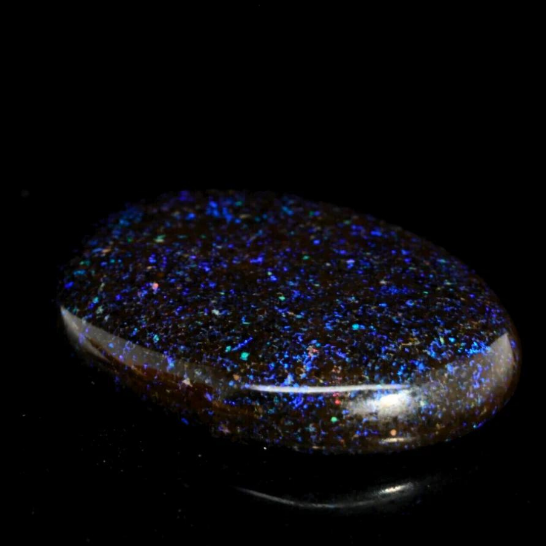 Andamooka Matrix Opal mit dunkler Grundfarbe und schimmernden blauen und violetten Flecken, auf schwarzem Hintergrund