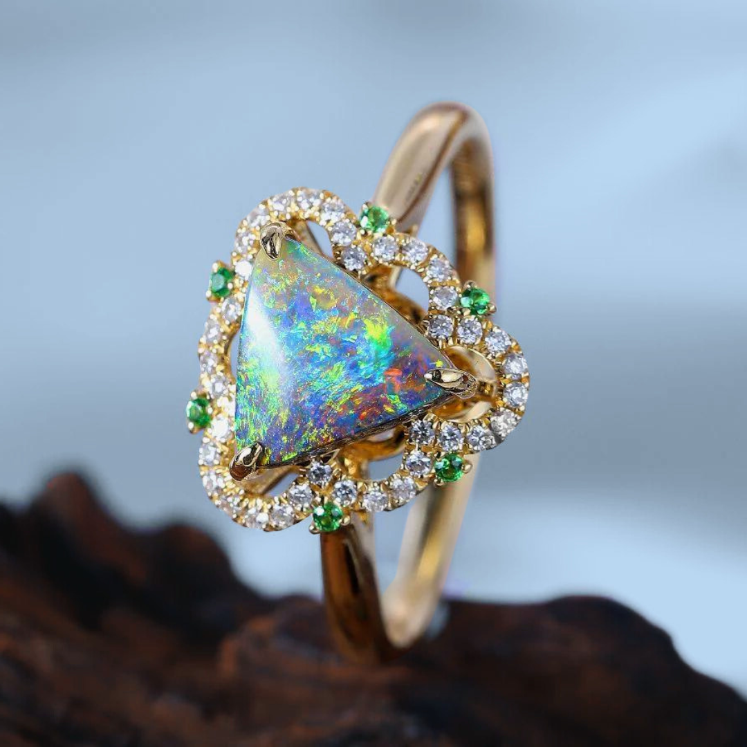 Goldring mit einem dreieckigen Opal, umgeben von 40 Diamanten und 6 Tsavoriten, präsentiert auf Holz